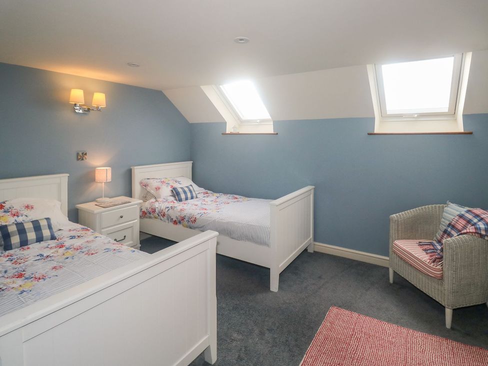 A bedroom with two beds and a chair at Higher Forda in Holsworthy