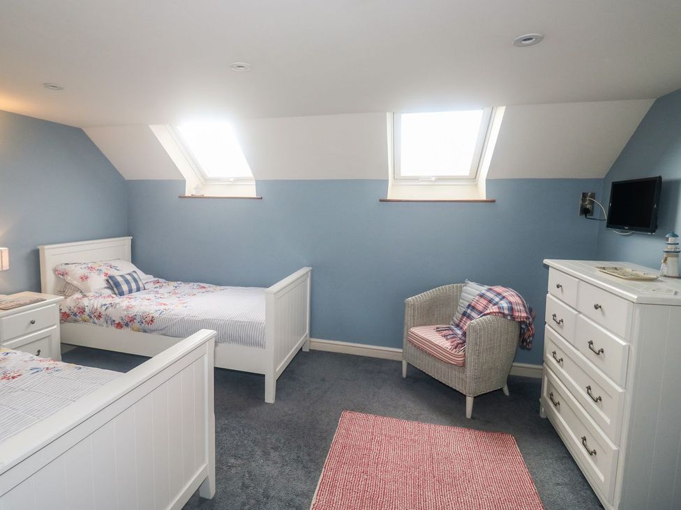 A bedroom with two beds and a dresser at Higher Forda in Holsworthy