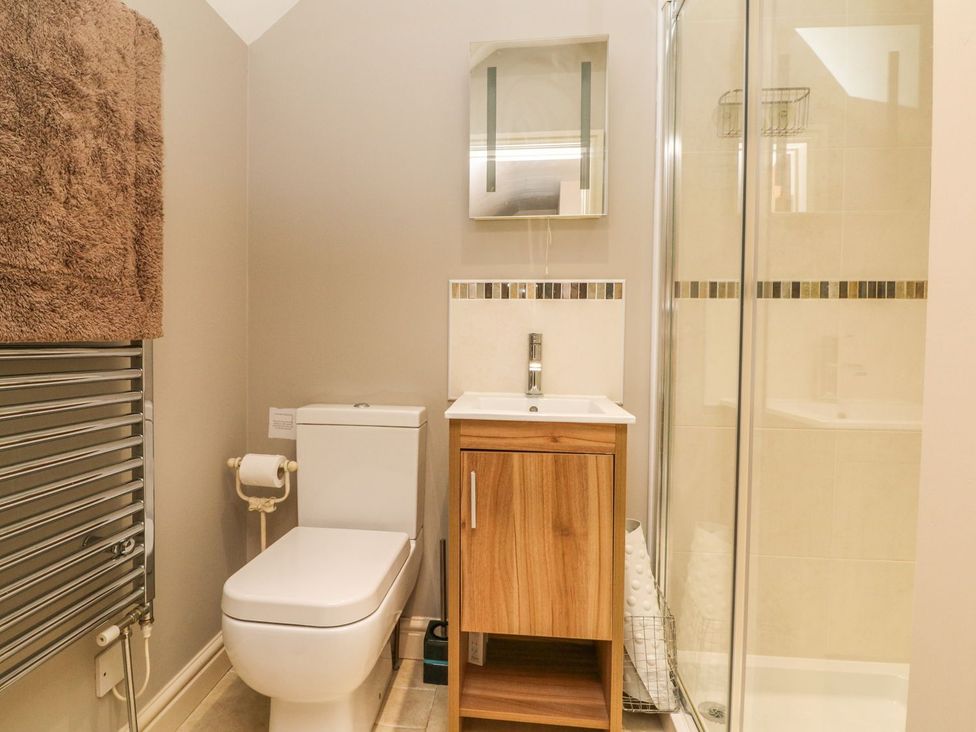 A bathroom with a toilet, sink, shower, and towel rack at Higher Forda in Holsworthy