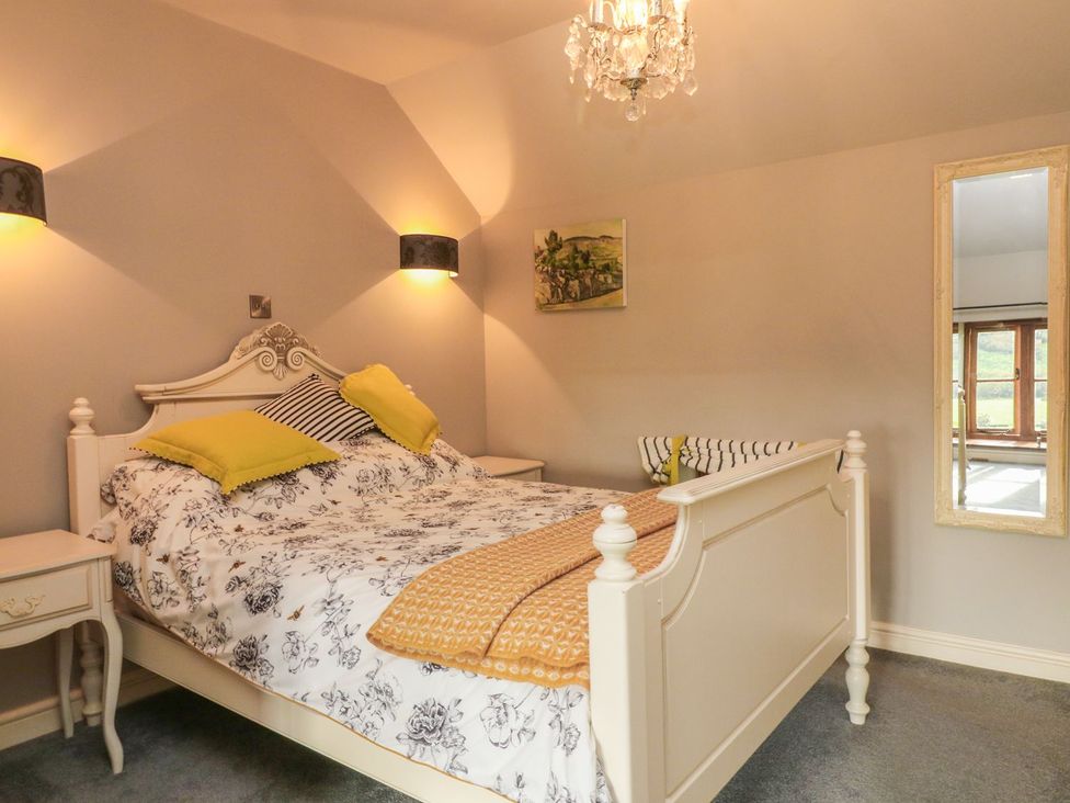 A bedroom with a bed and a mirror at Higher Forda in Holsworthy