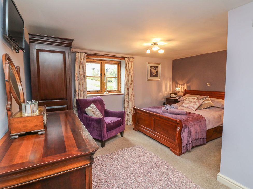 A bedroom with a double bed and an armchair at Higher Forda in Holsworthy