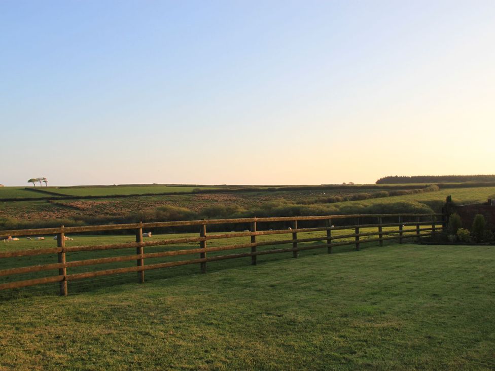An outdoor area with a fence and hills at Higher Forda in Holsworthy