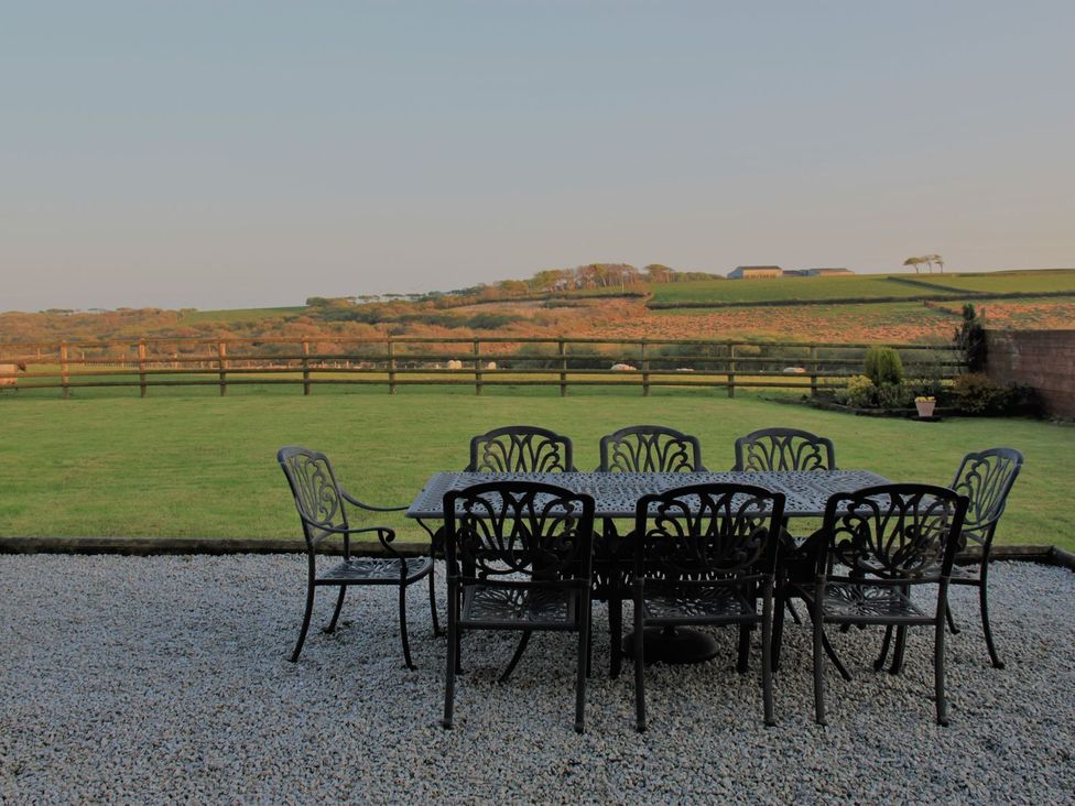 A garden with a table and chairs at Higher Forda in Holsworthy