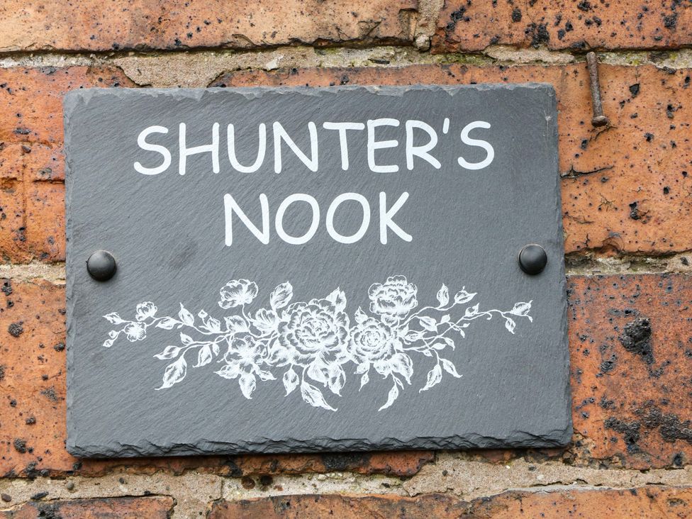 A slate sign that reads Shunter's Nook attached to a brick wall in Stafford
