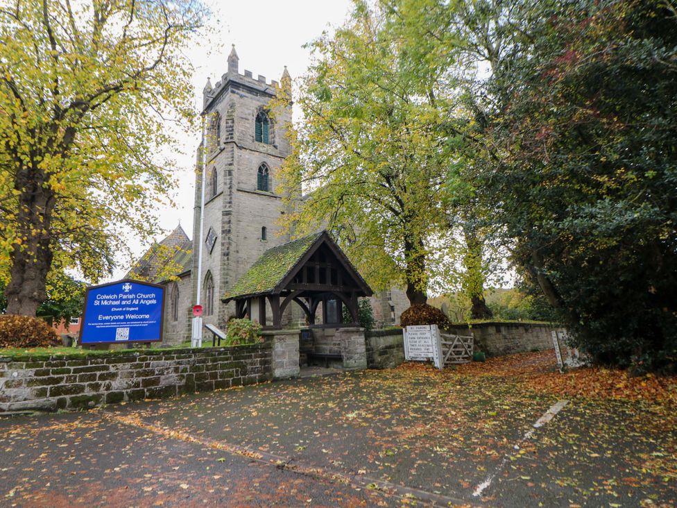 A church with a sign and trees at Colwich Parish Church in Stafford