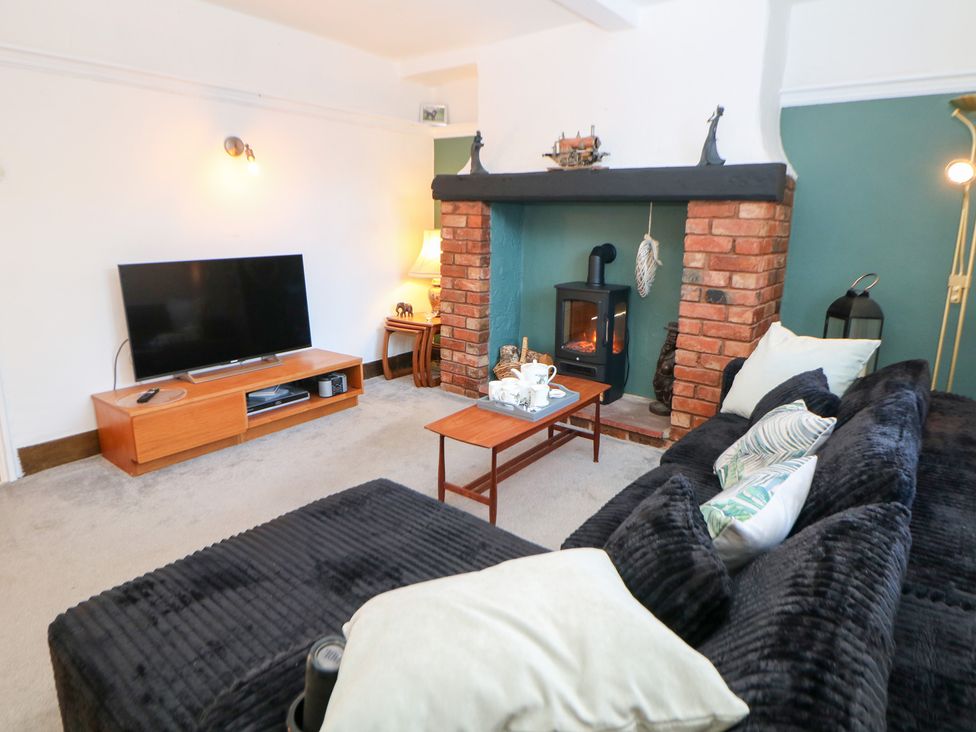 A living room with a television, coffee table, and fireplace at Shunter’s Nook in Colwich