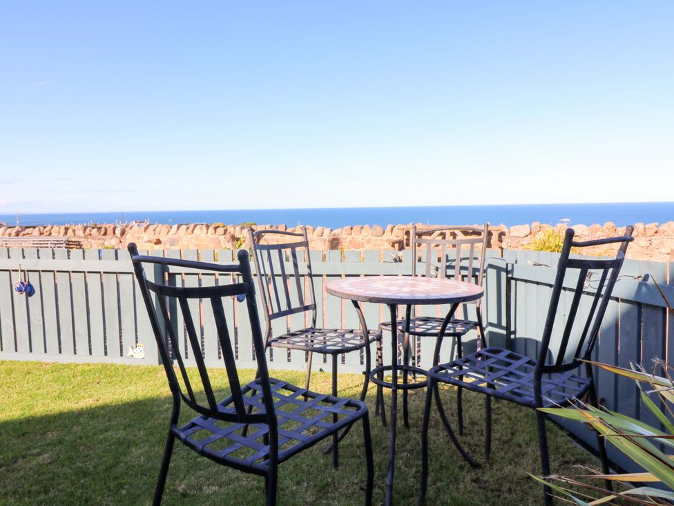 A garden with table and chairs overlooking the sea at Bridle Cottage in Cockburnspath
