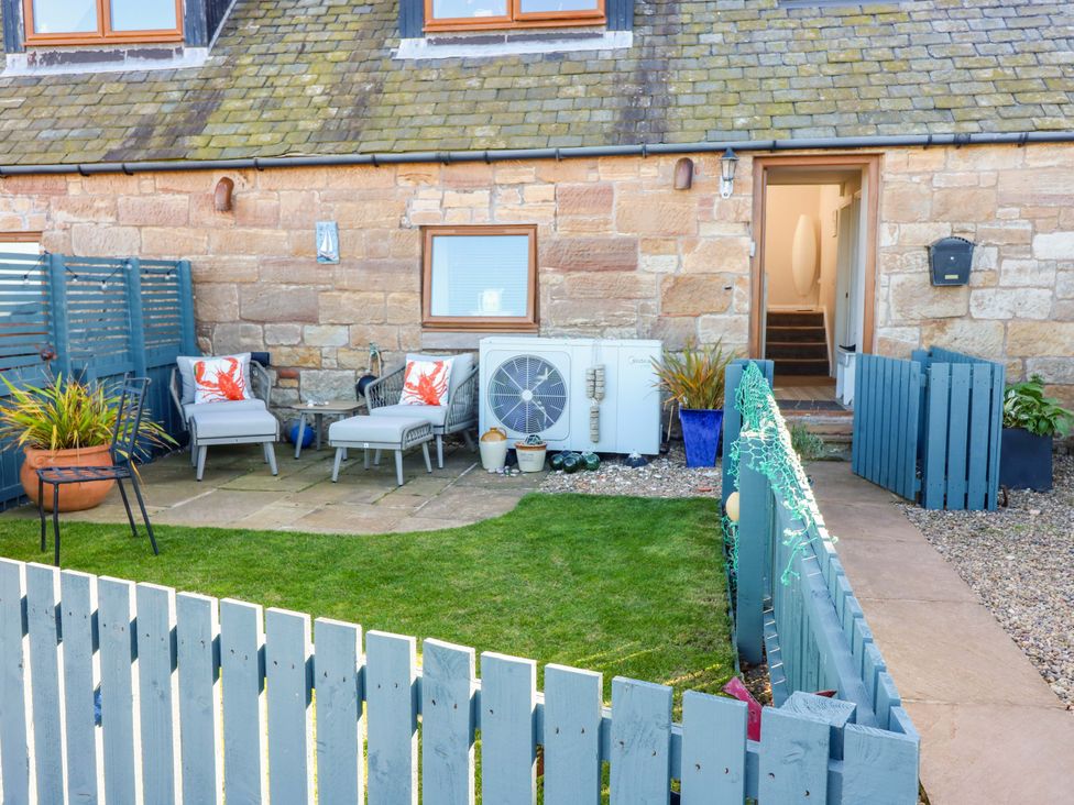 A garden with chairs and an air conditioning unit at Bridle Cottage, Cockburnspath