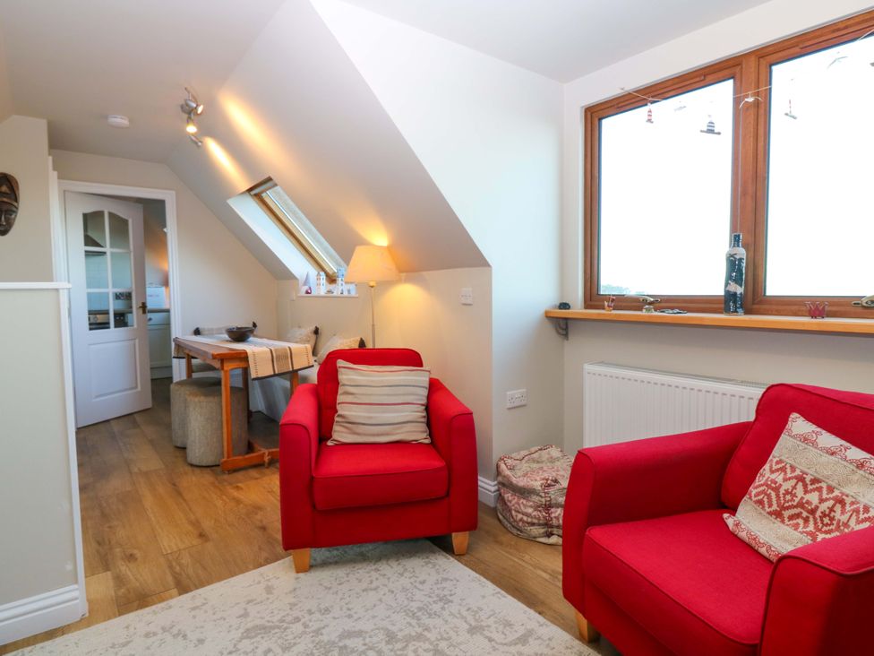 A living room with red armchairs and a table at Bridle Cottage in Cove