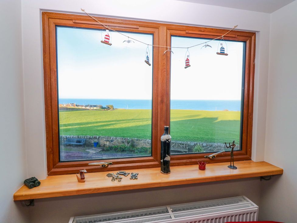 A living room window view showing ocean and green field at Bridle Cottage in Cove