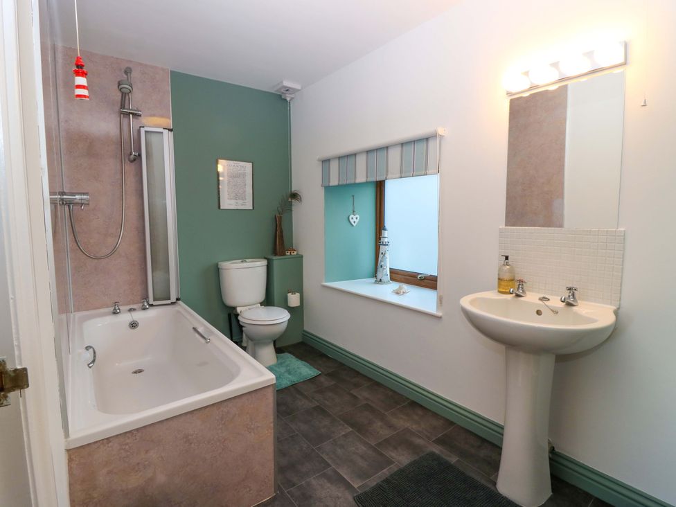 A bathroom with a bath, shower, toilet, and sink at Bridle Cottage in Cove