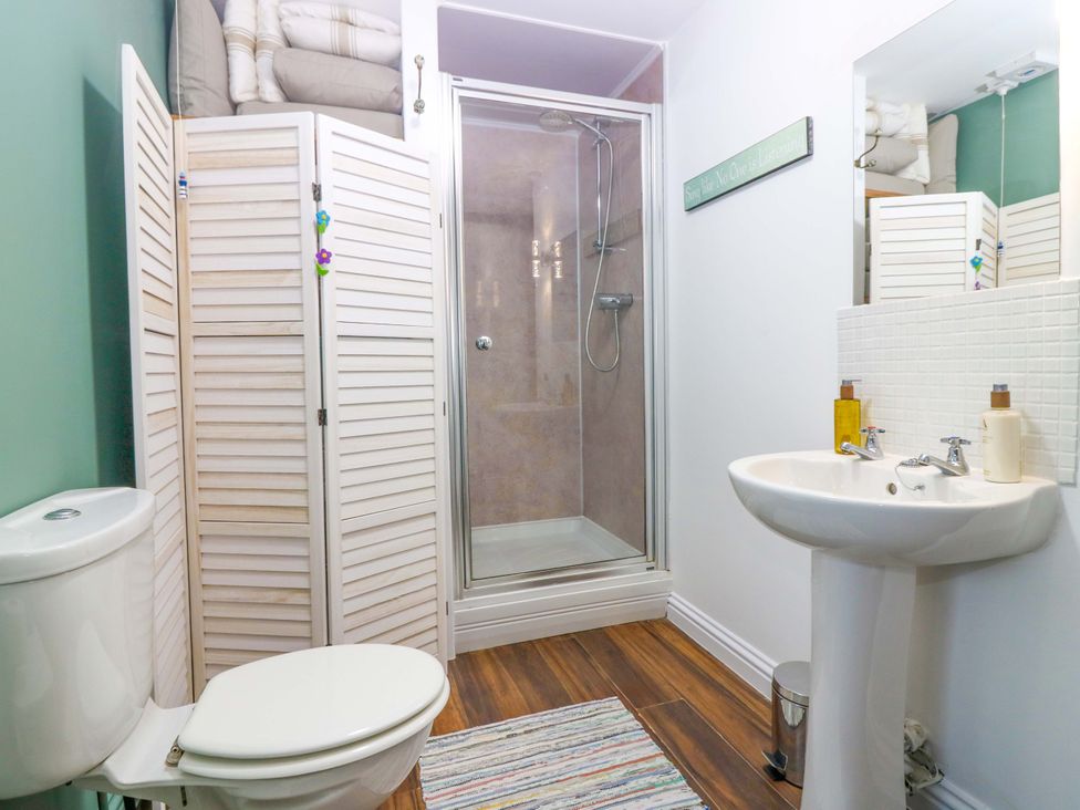 A bathroom with a shower, toilet, and sink at Bridle Cottage Cove