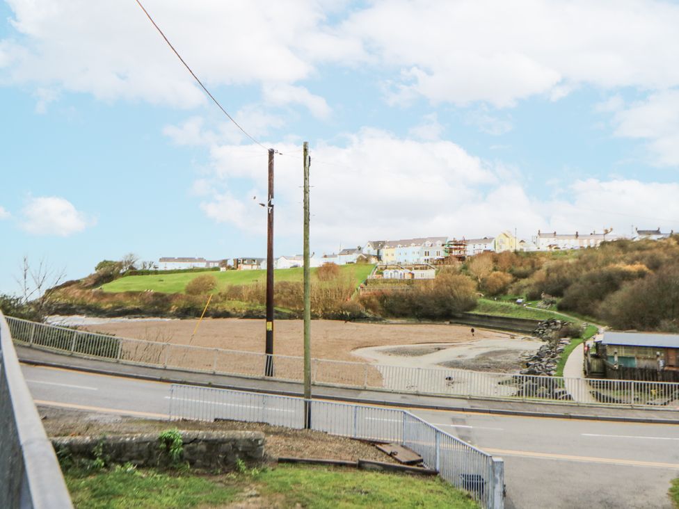 A view of houses on a hill with a road and trees at Fronglyd Aberporth