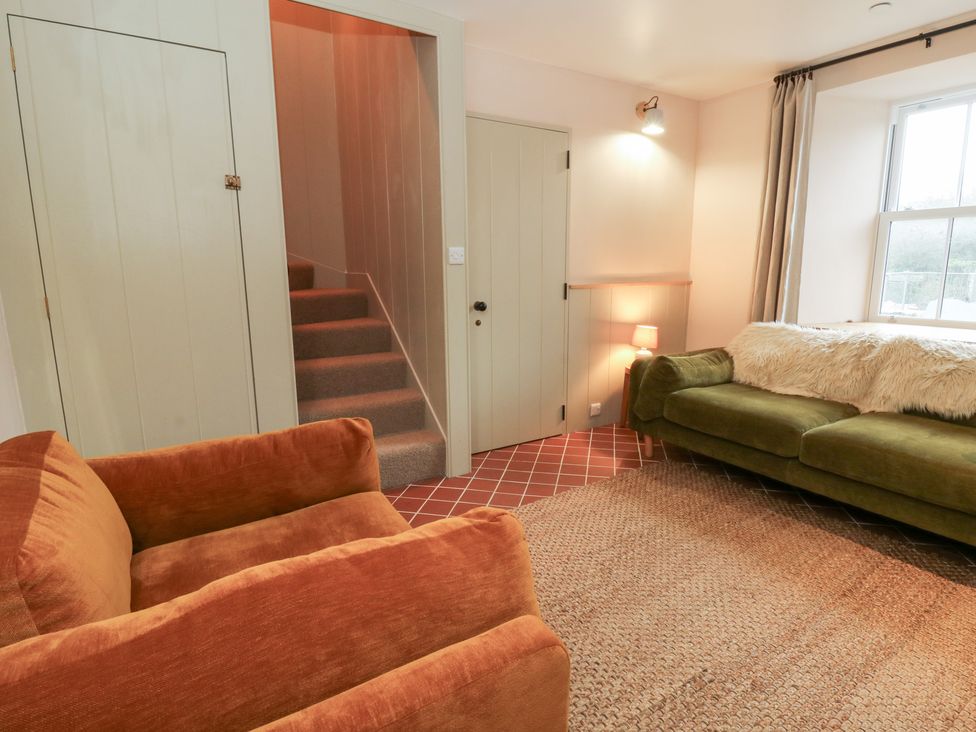 A living room with a sofa, armchair, and stairs at Fronglyd in Aberporth