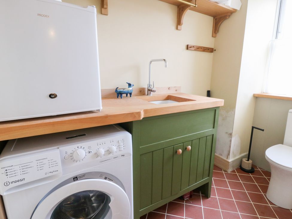 A laundry room with a washing machine and sink at Fronglyd Aberporth