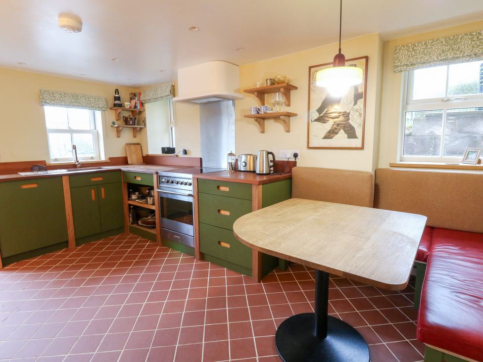 A kitchen with a table, kettle, and oven at Fronglyd in Aberporth