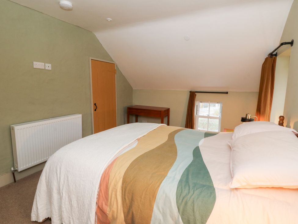 A bedroom with a bed, radiator, table and window at Fronglyd Aberporth