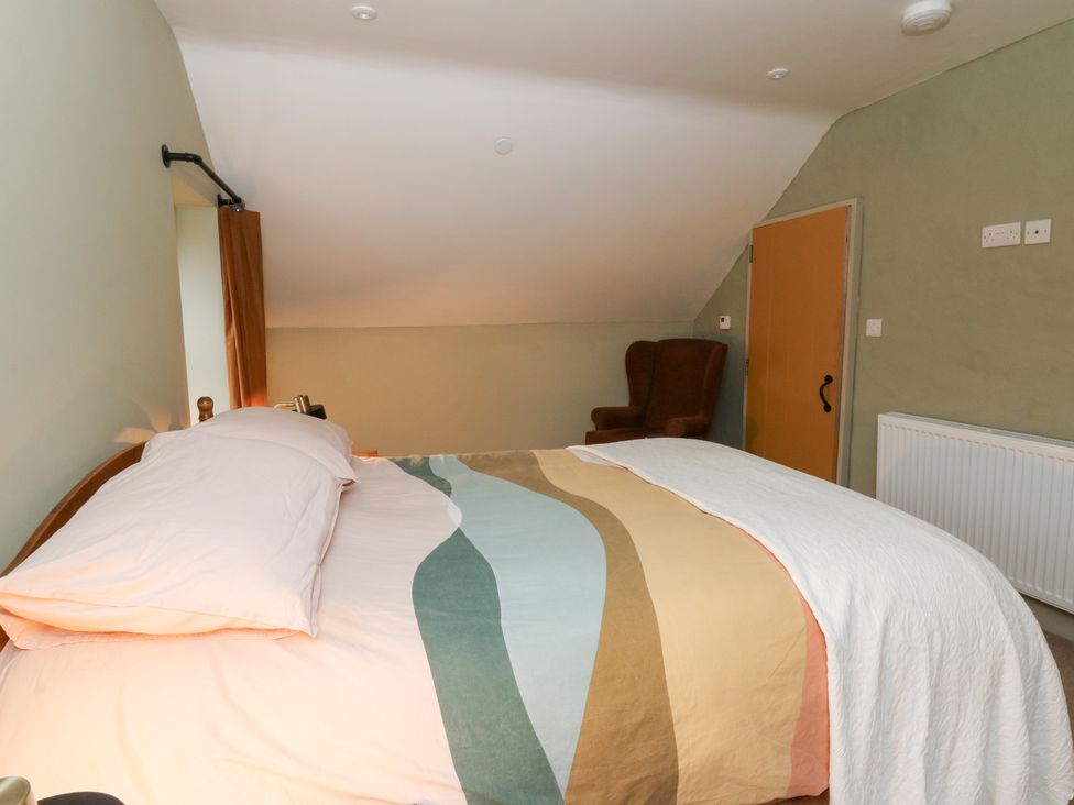 A bedroom with a bed and chair at Fronglyd Aberporth