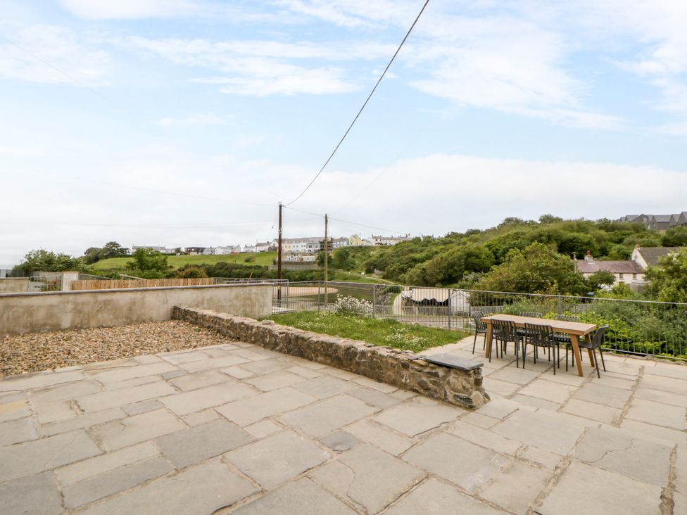 A garden with a table and chairs overlooking a hillside at Fronglyd Aberporth