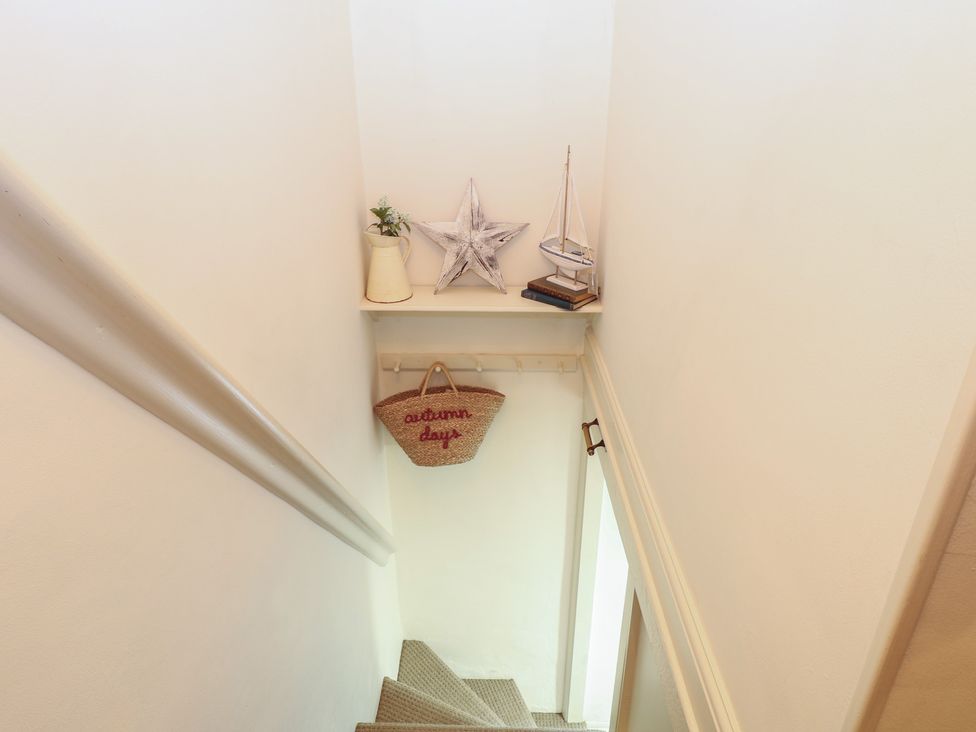 A staircase with a shelf holding a star and a boat at Beeble Cottage in Fakenham