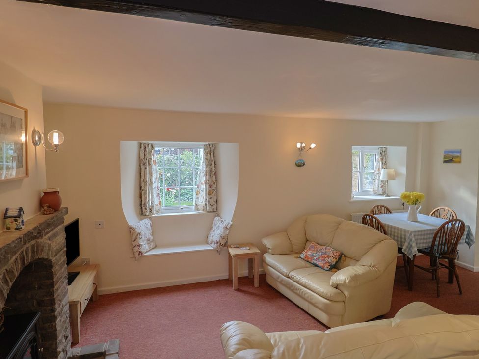 A living room with a sofa and dining table at Vine Cottage in Burton Bradstock