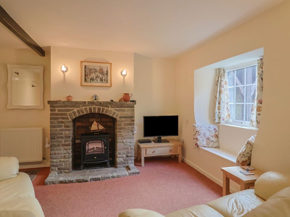A living room with a fireplace and television at Vine Cottage in Burton Bradstock
