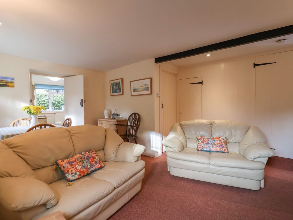 A living room with sofas and a table at Vine Cottage in Burton Bradstock