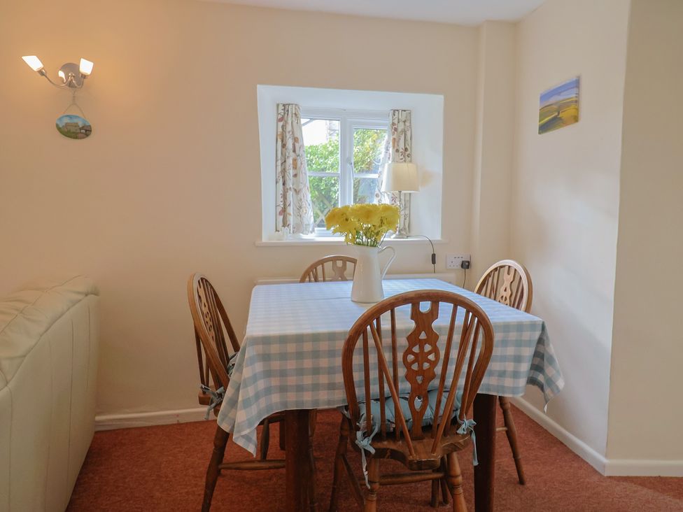 A dining room with a table and chairs at Vine Cottage in Burton Bradstock