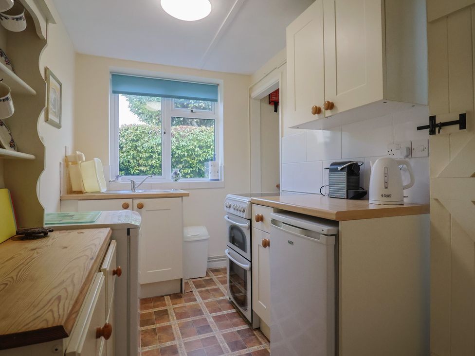 A kitchen with cabinets and appliances at Vine Cottage in Burton Bradstock