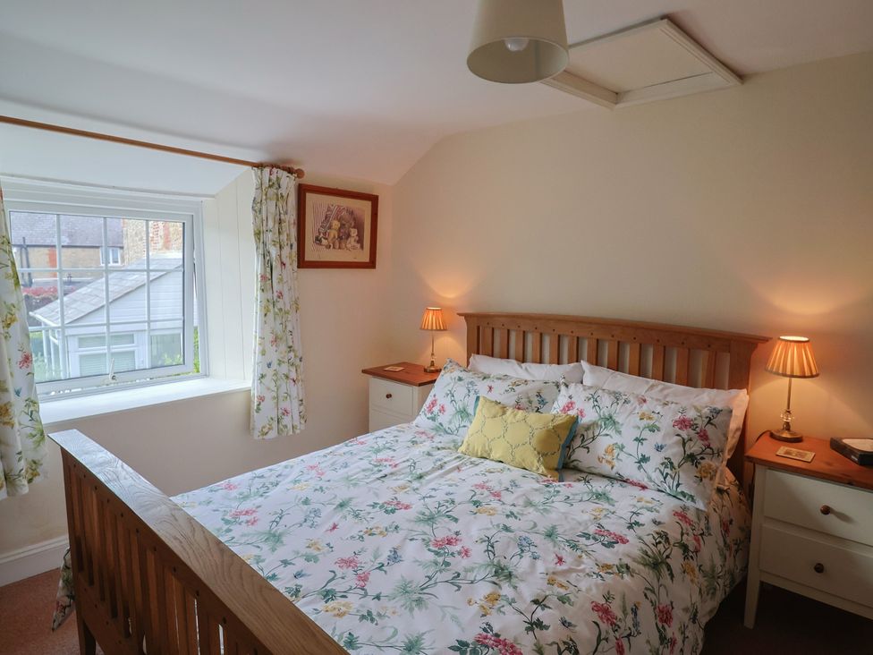 A bedroom with a bed and window at Vine Cottage in Burton Bradstock