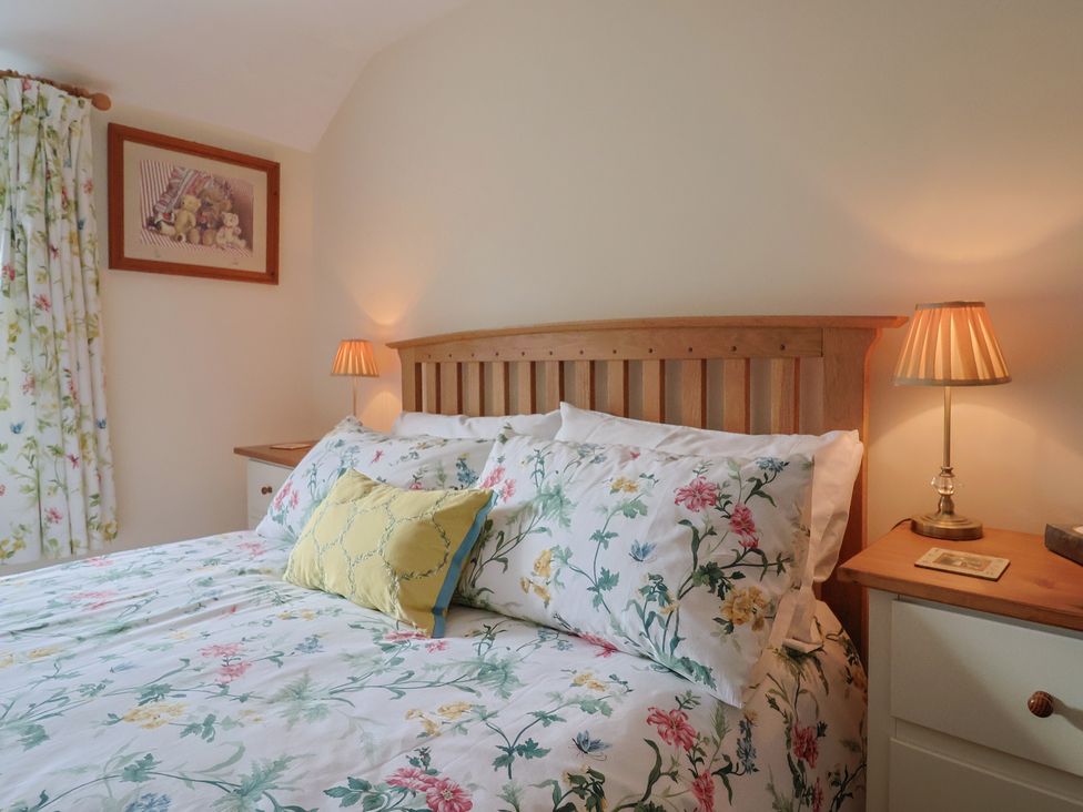 A bedroom with a bed and bedside lamp at Vine Cottage in Burton Bradstock