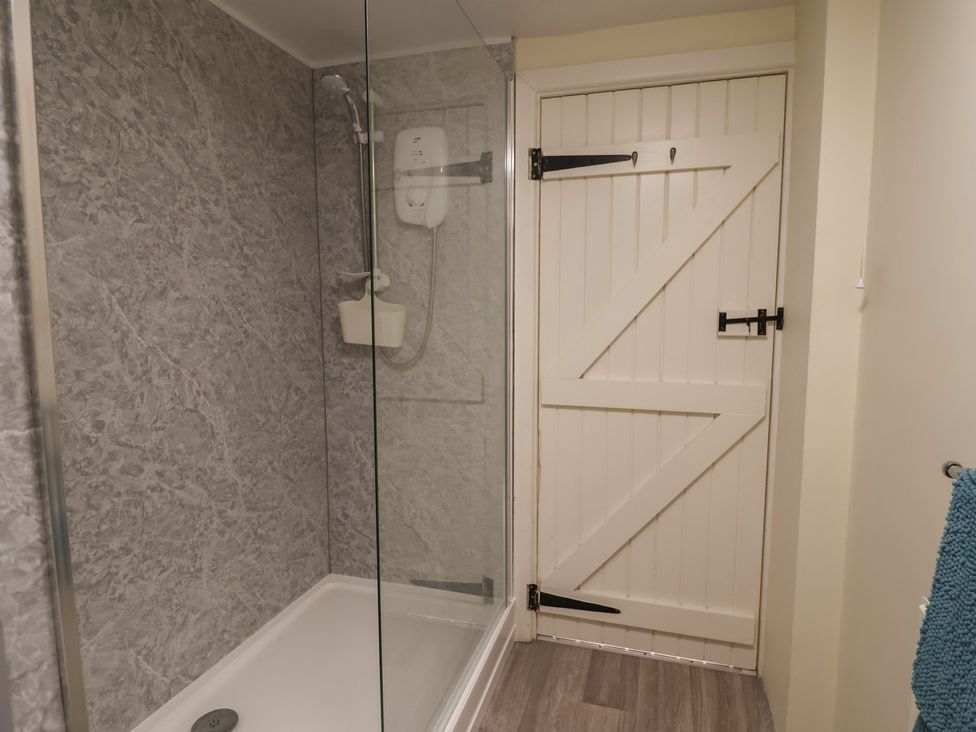 A bathroom with a shower and a door at Vine Cottage in Burton Bradstock