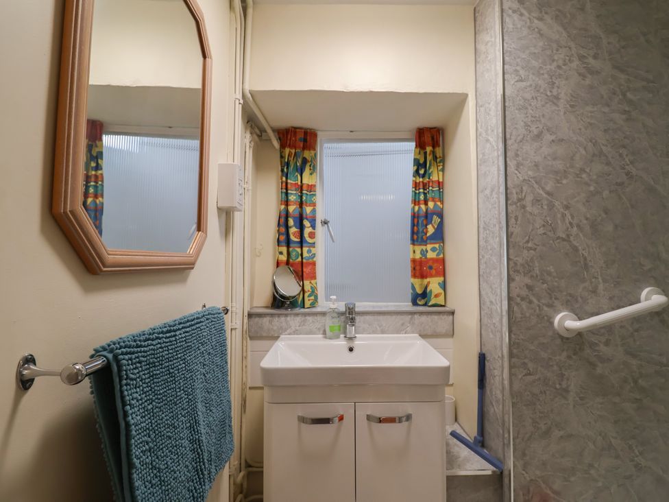 A bathroom with a sink and mirror at Vine Cottage in Burton Bradstock