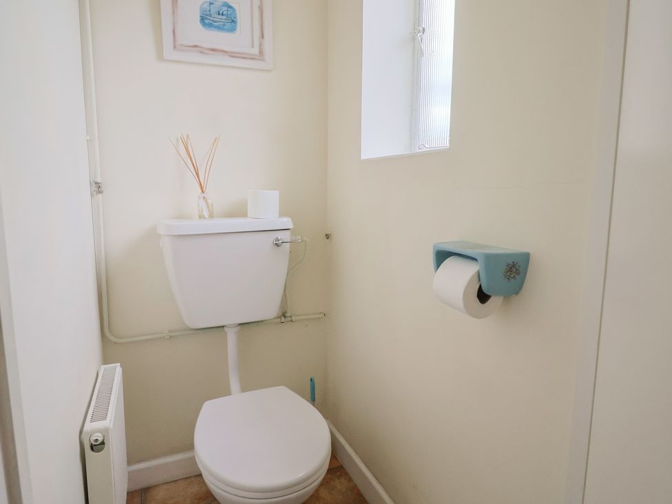 A bathroom with a toilet and window at Vine Cottage in Burton Bradstock
