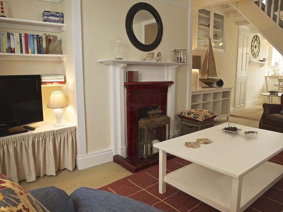 A living room with a fireplace and a television at St Leonards in Salcombe
