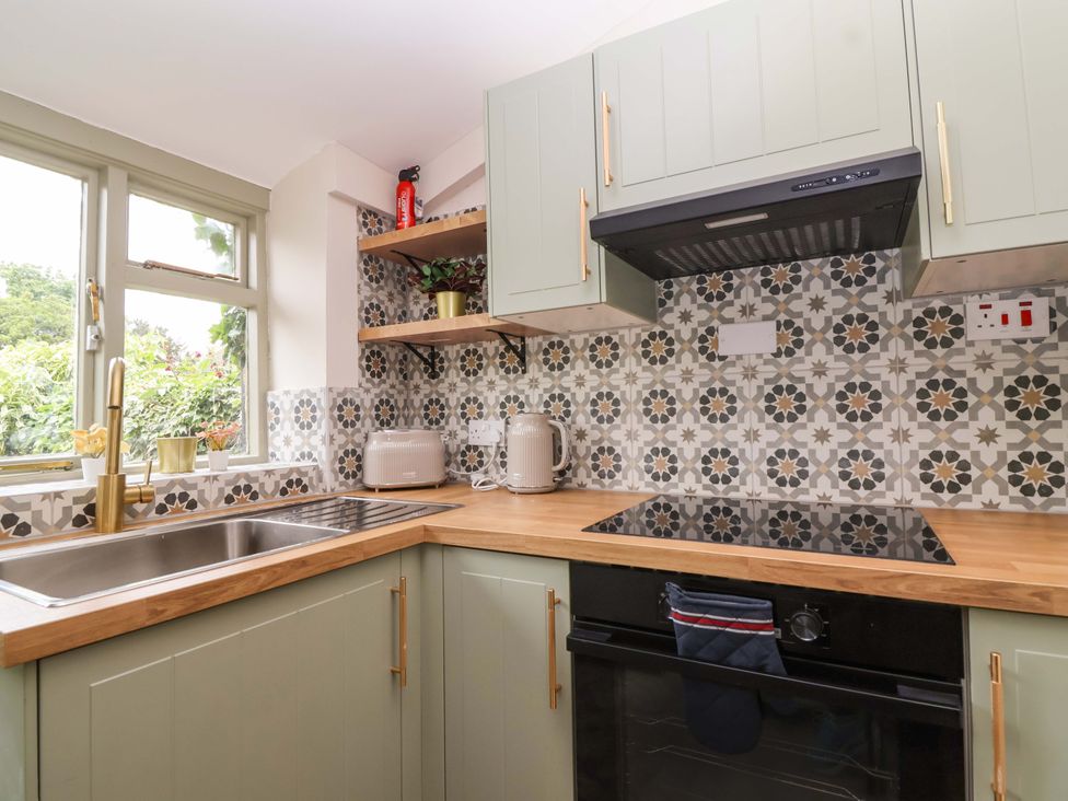 A kitchen with sink, stove, and shelf at 29 Spring Street in Chipping Norton