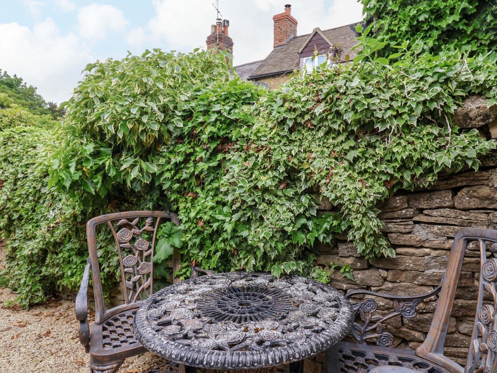 A garden with a stone wall and a table with chairs at 29 Spring Street Chipping Norton