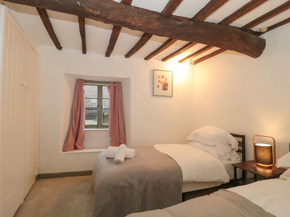 A bedroom with two beds and a window at 6 Priory Lane Burford