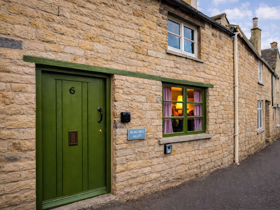 A green door and window on a stone building at Burford Apple in Burford