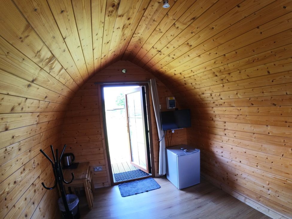 A room with a door, television, and fridge at Rosebud Meadow Pod 1