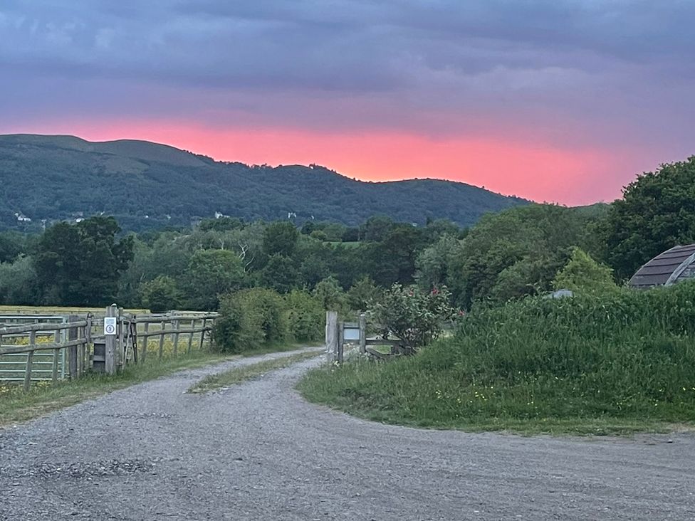 A view of mountains and sky at sunset with a gravel path and fence