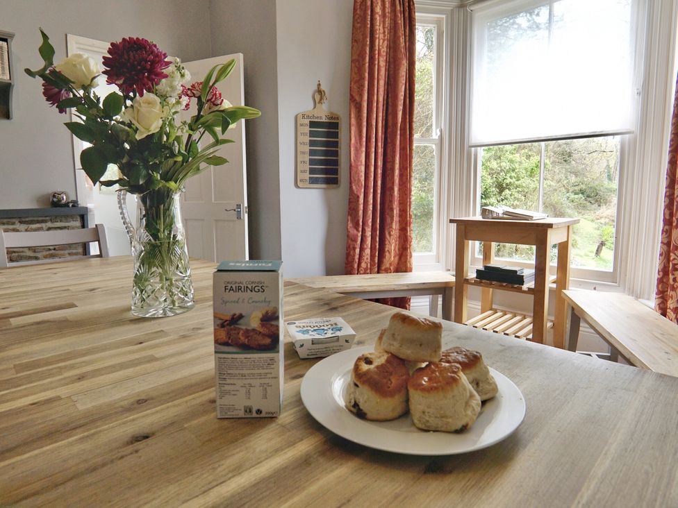 A kitchen with flowers on a table and scones at Roselyn House in Par
