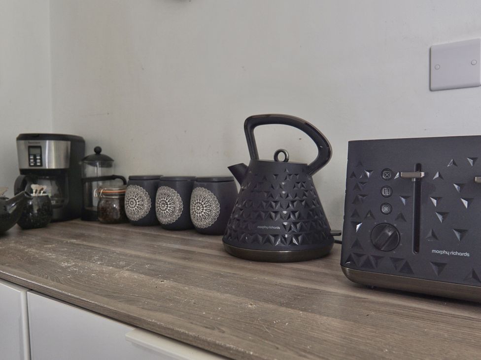 A kitchen countertop with kettle, toaster, coffee maker, jars and mugs at Roselyn House in Par