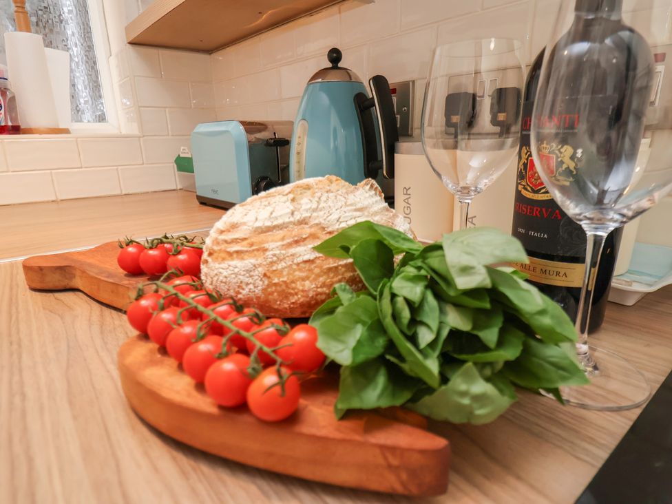 A kitchen with bread, tomatoes, basil, and wine at Farriers Yard, Whitby