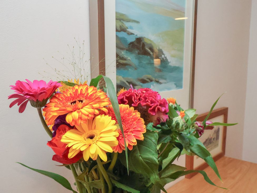 A display of flowers in a vase with a painting in the background at Farriers Yard, Whitby