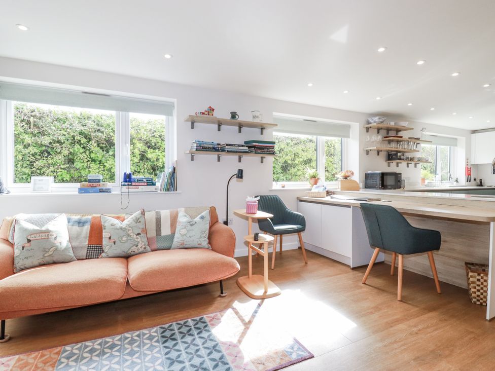 A living room with a sofa and a kitchen area at Hillbre in Trevone