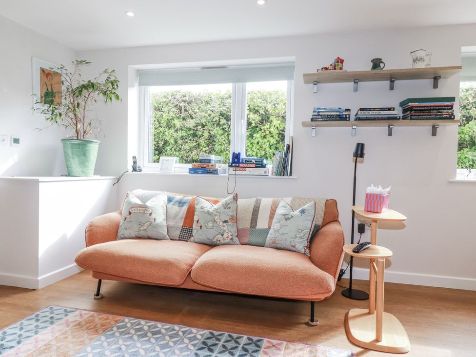 A living room with a sofa, bookshelf, and plant at Hillbre in Trevone