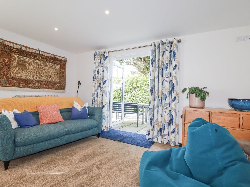 A living room with a couch and door leading to a patio at Hillbre Trevone