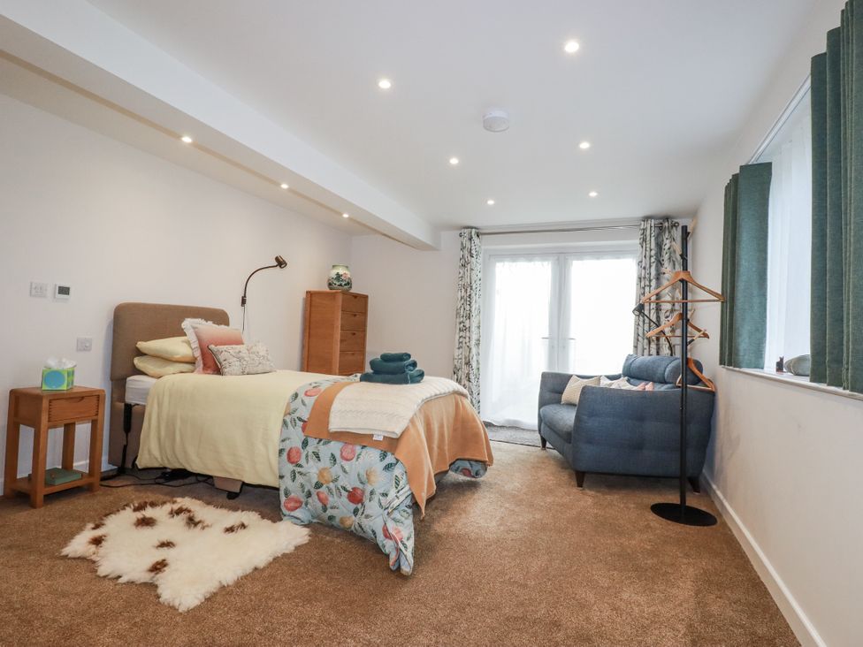 A bedroom with a bed, sofa, and curtains at Hillbre Trevone