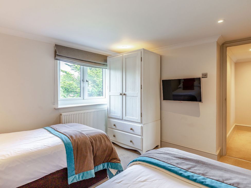 A bedroom with two beds and a wardrobe at Summerleaze Cottage 2 Spa Bude